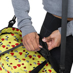 Daemon Luxury Foreigners Luv Solar Butter all-over-print duffle bag in white with bold, colorful design and sturdy handles.