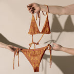 Daemon Luxury Tarmin Dim Sun Glow Dulce Scusa all-over-print recycled string bikini in white, front view showing vibrant sun-inspired design.