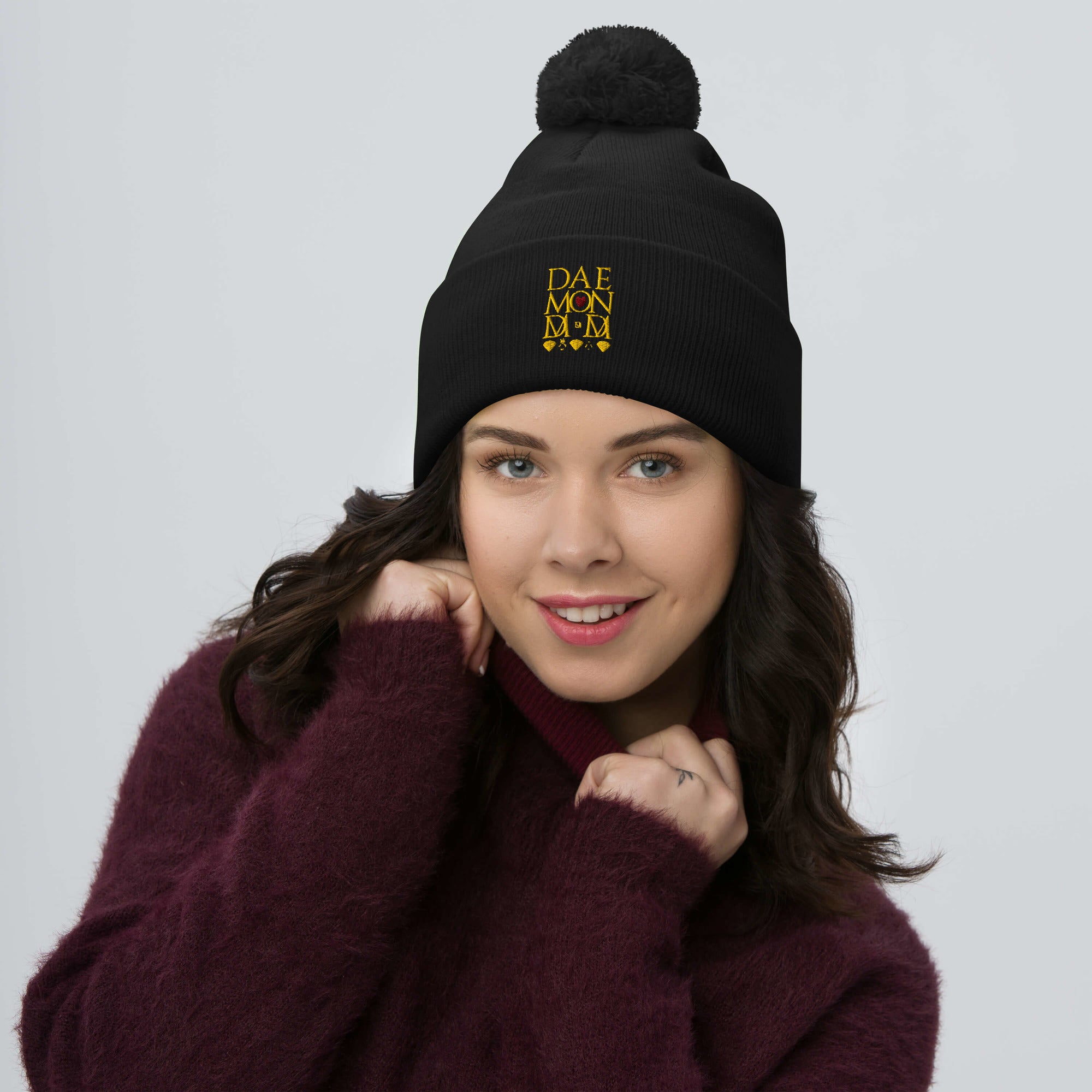 Daemon Luxury Nemesis Sun Glow black knit wool beret with pom-pom detail, front view showing cozy, stylish winter headwear.