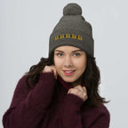 Daemon Luxury Stormless Dim (Sun Glow) pom-pom-knit wool cap in dark heather grey, front view showing cozy knit texture.